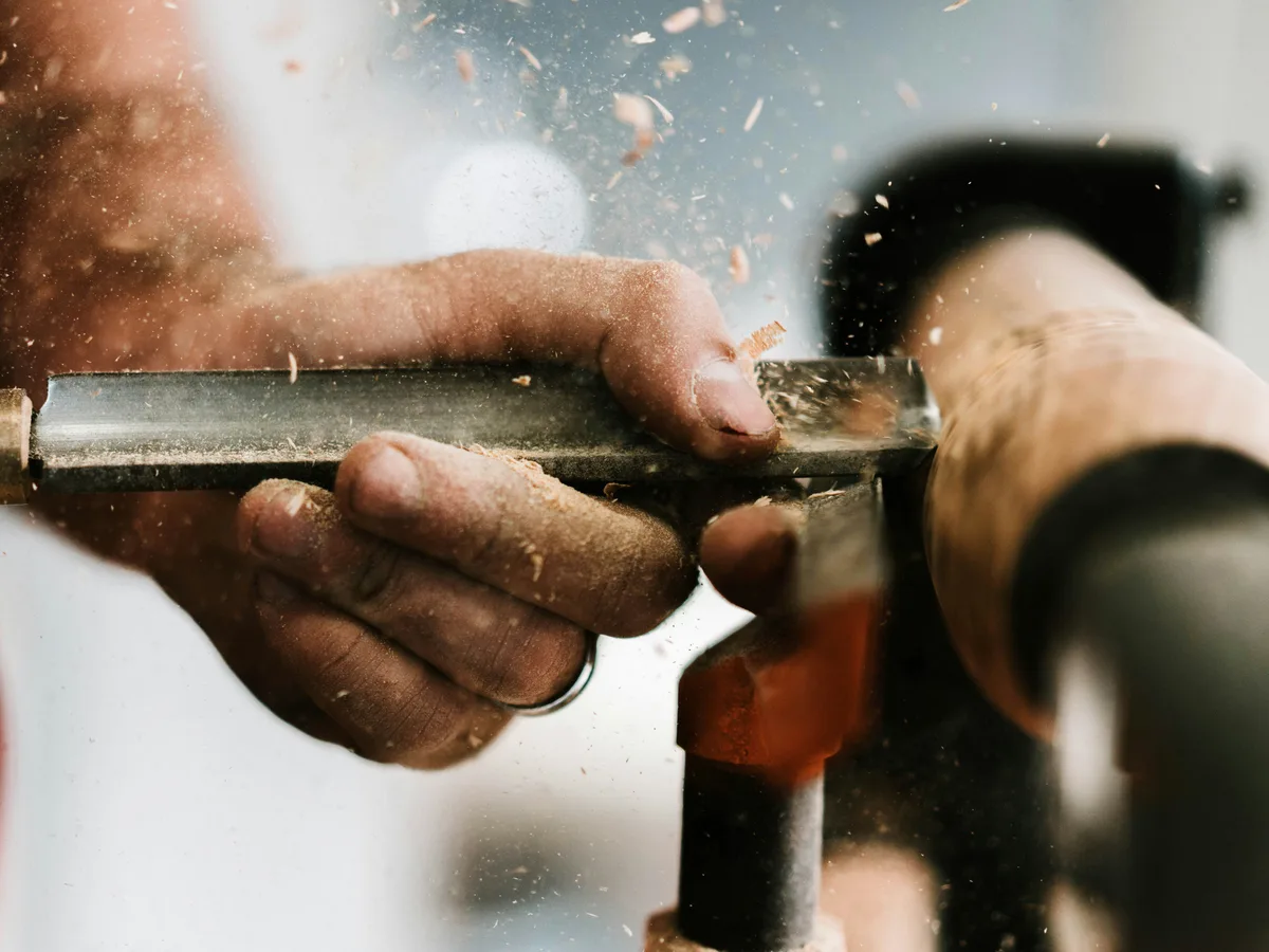 Hands cutting a copper pipe with a pipe cutter