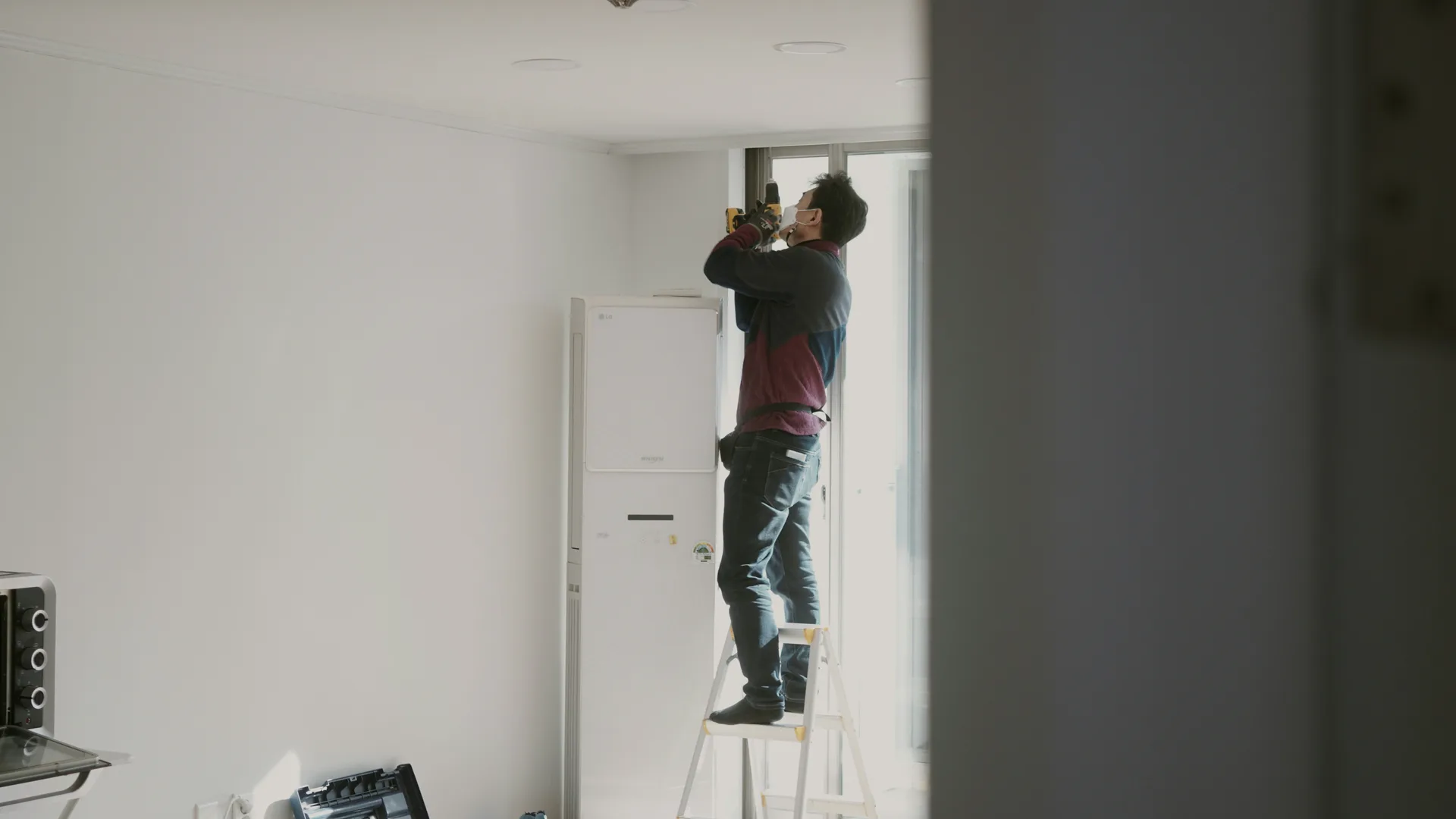 An electrician on a ladder first-fixing a bright new room