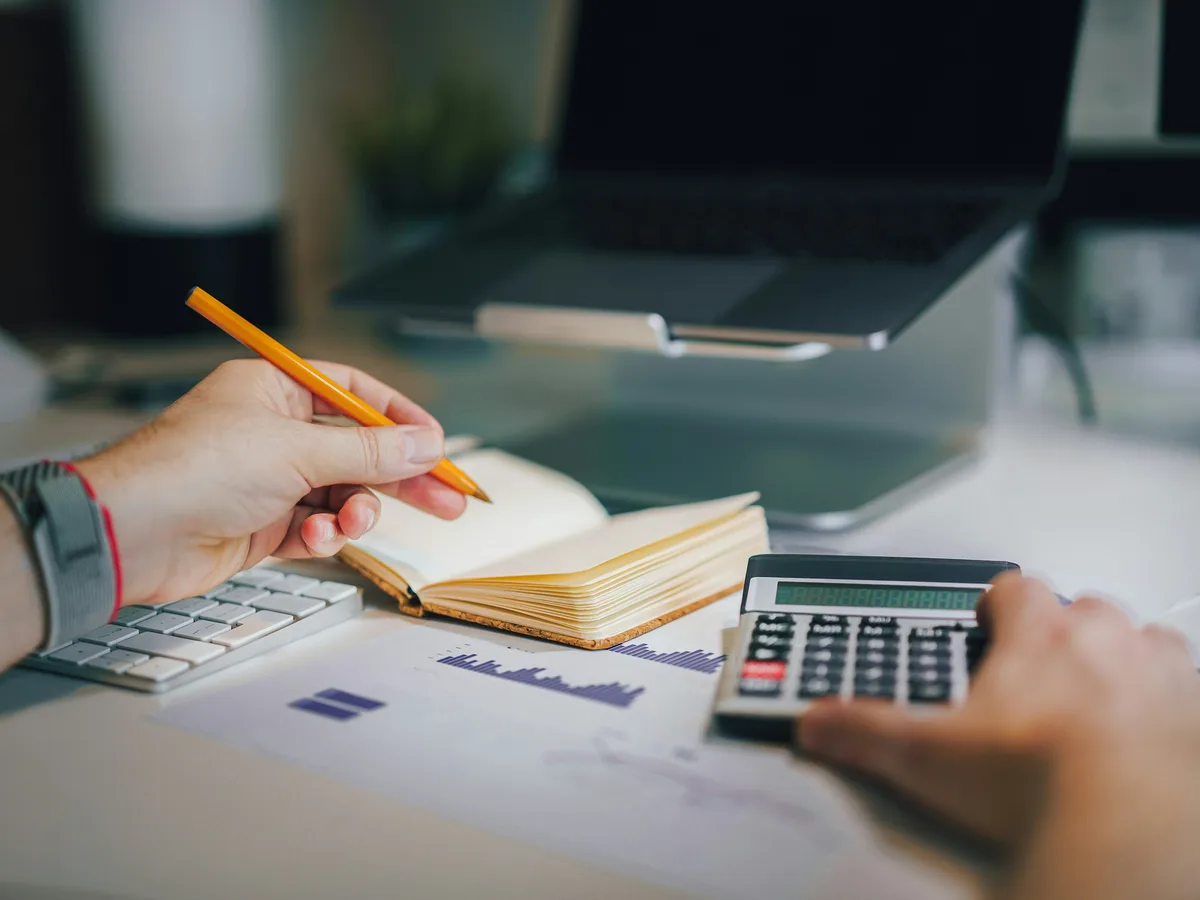 Hands working through a ledger with a calculator