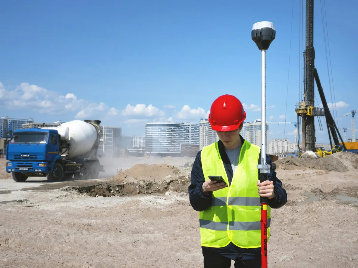A tradesperson in hi-vis checking their phone on site