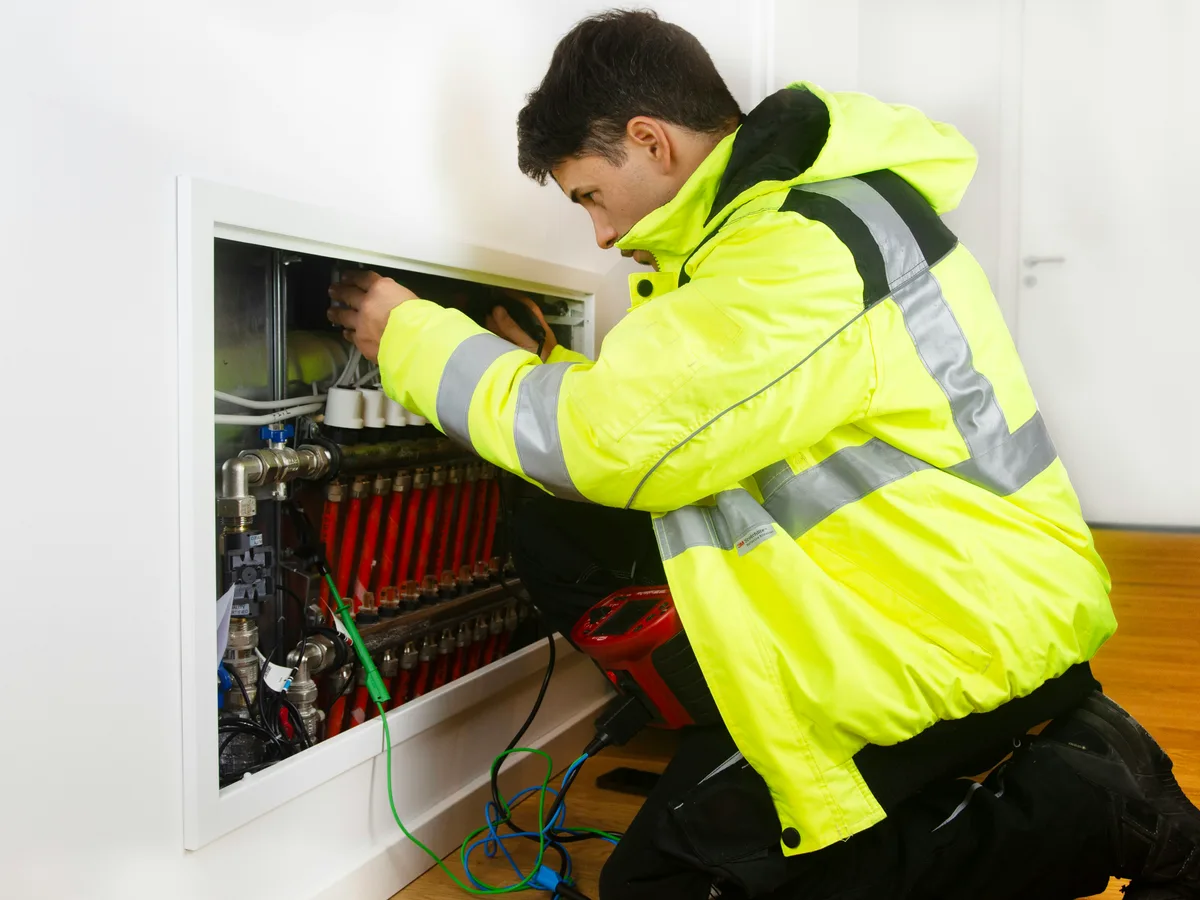 An engineer in hi-vis working on a control panel mid-job