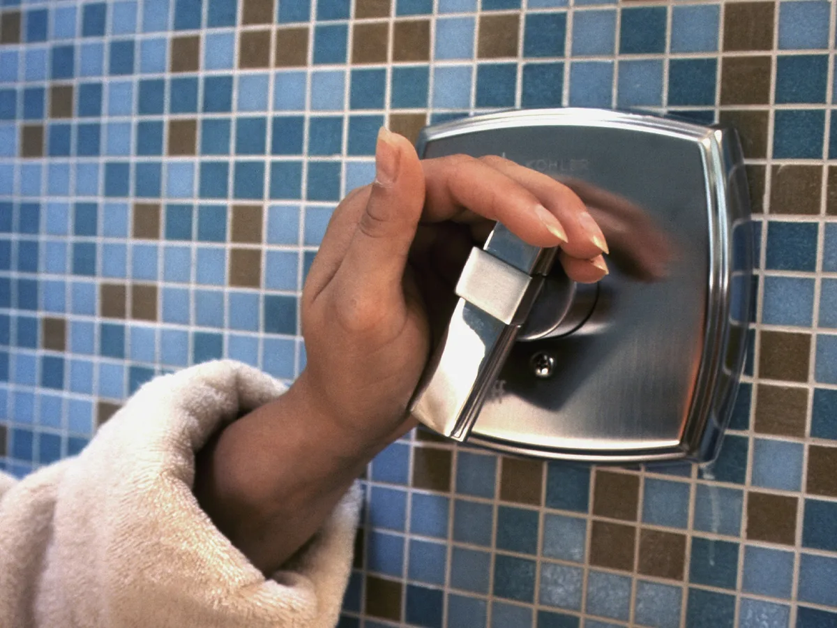 Hands refitting a tap on blue mosaic tiles